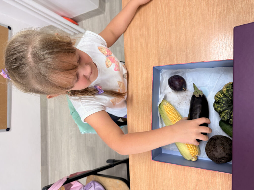 Dziewczynka odgaduje zagadkę sensoryczną z pudełka z zamkniętymi oczami.