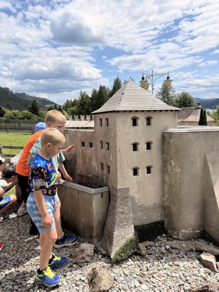 Uczniowie podziwiają zamek w miniaturowym parku rozrywki.